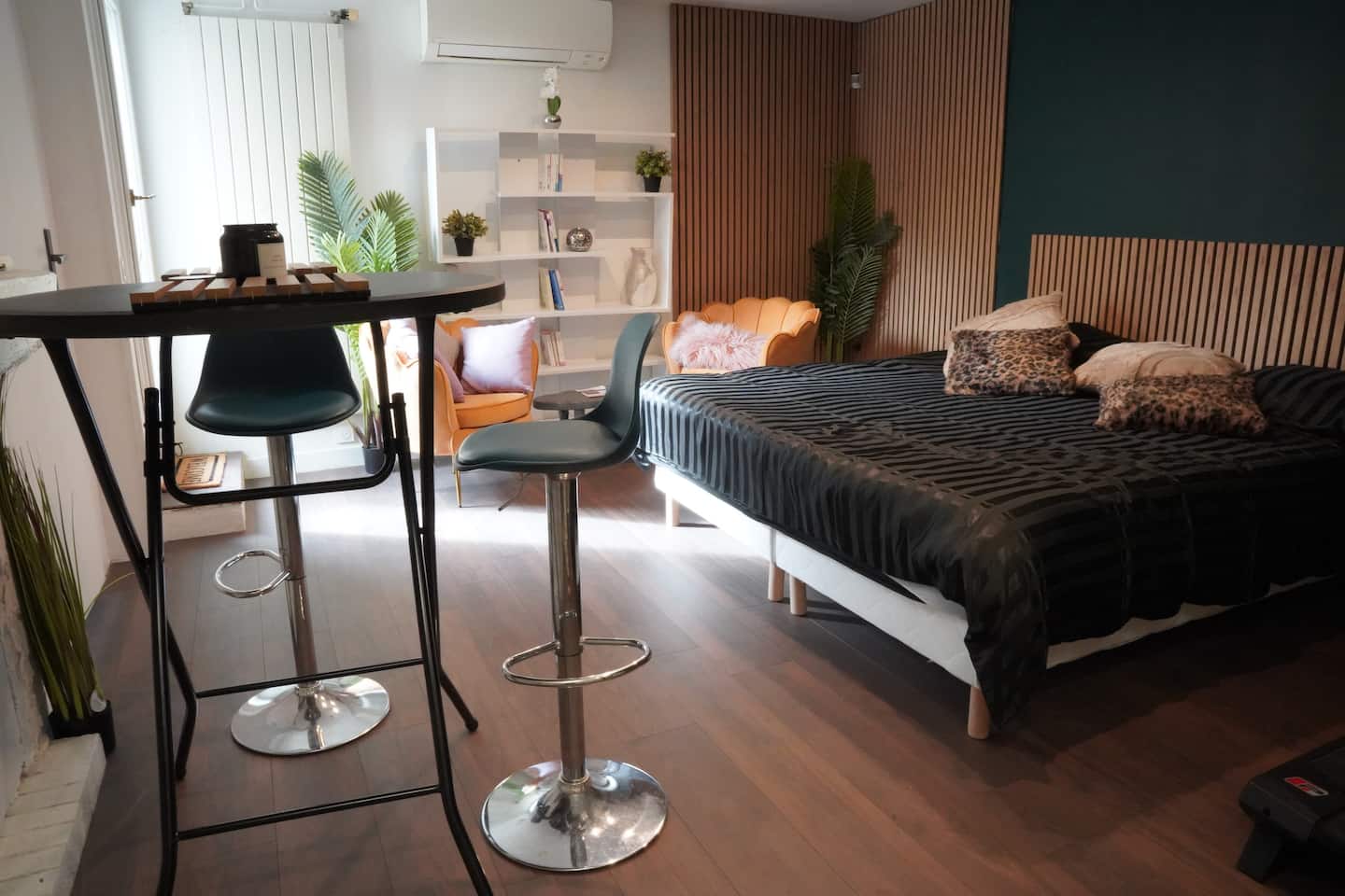 Le coin repas avec sa table haute et ses tabourets, face au lit