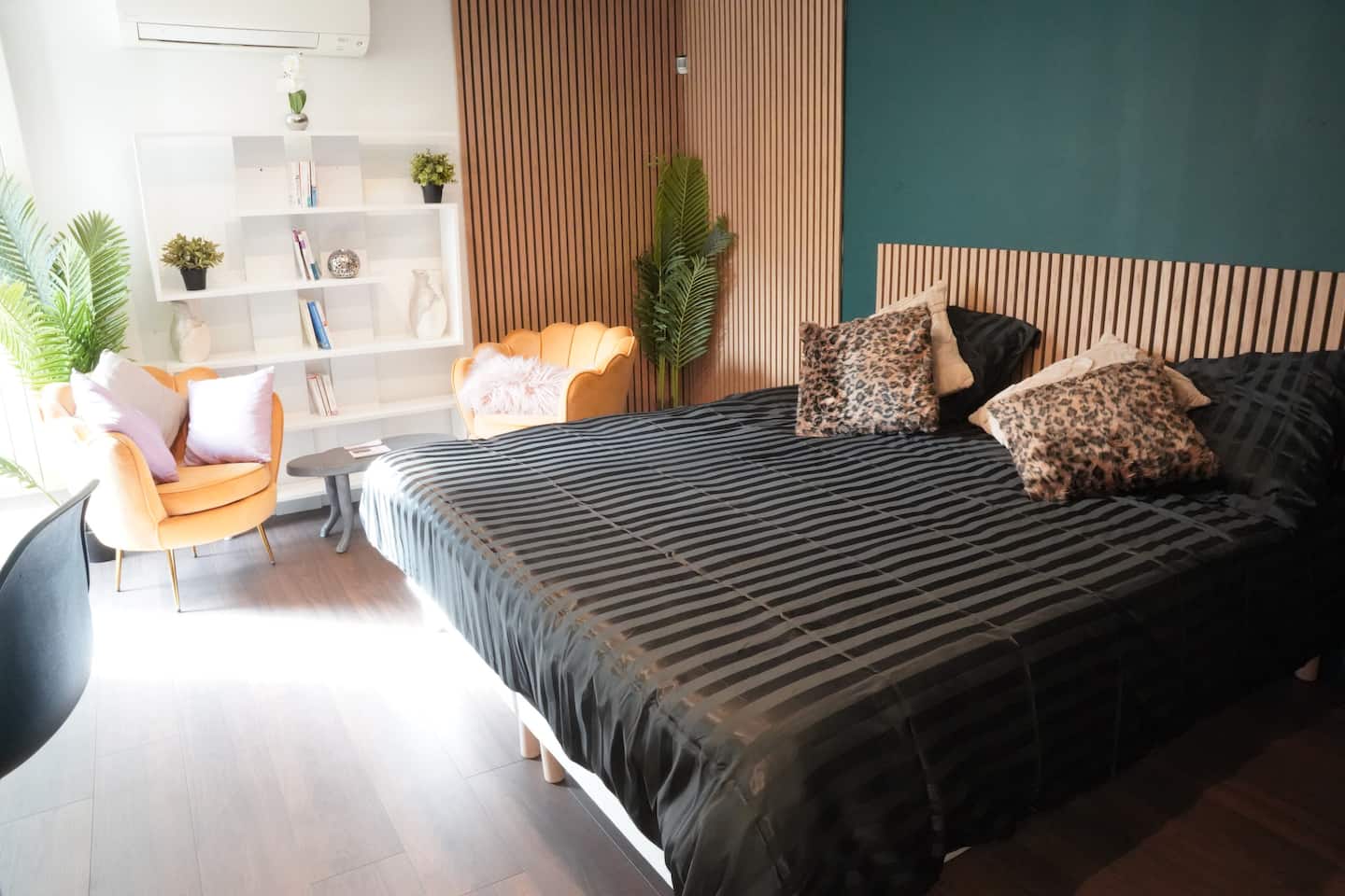 La chambre privée avec son lit double, son coin salon et son mur en tasseaux de bois