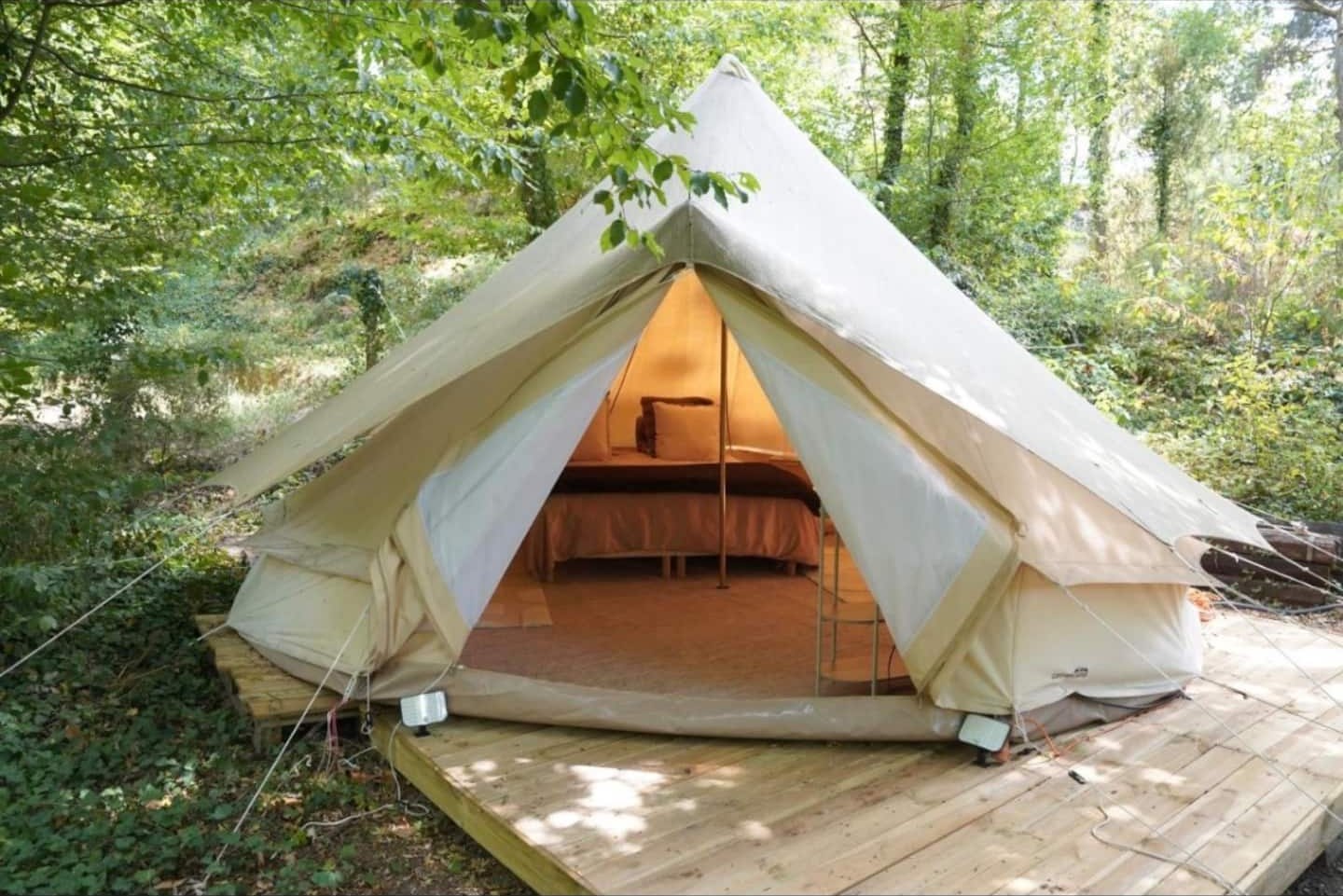 La yourte installée sur sa terrasse en bois, ouverte sur la forêt